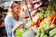 © NDABCREATIVITY - Young woman buying vegetable on stall at the market