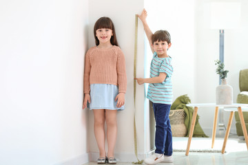 Poster - Cute little children measuring height near wall