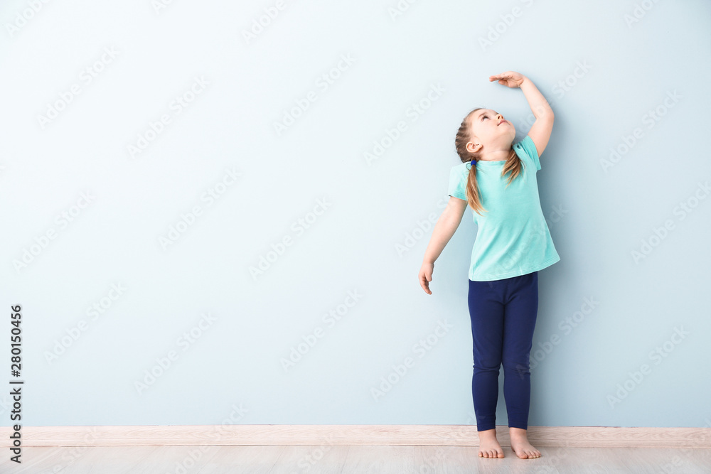 Little girl measuring height near wall