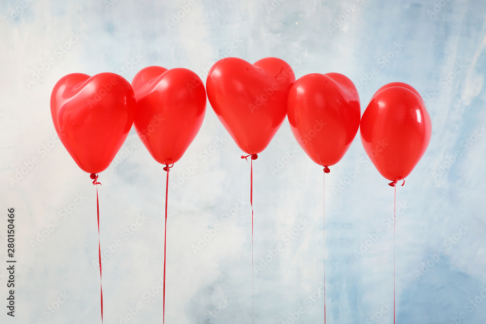 Heart-shaped air balloons on color background
