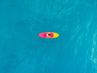Wall Mural - Woman relaxing on stand up paddle board on a quiet blue sea. Aerial view