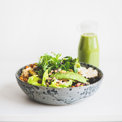 Healthy dinner or lunch. Vegan superbowl or Buddha bowl with hummus, vegetable, fresh salad, beans, couscous and avocado and green smoothie in bottle over white background, copy space, square crop