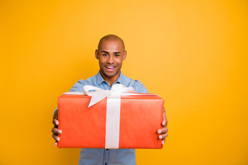 Portrait of cute friendly man hold hand gift box red white ribbon isolated over yellow background