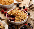 Mixed berry (blackberry, raspberry) crumble in a baking dish on a wooden table, close-up
