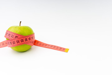 Green apple with red measuring tape. Selective focus