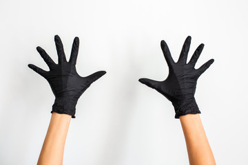 A hand wearing black glove with spread fingers on a white background