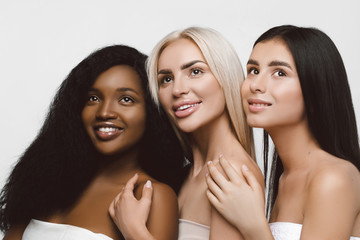 Wall Mural - Three different nation girls with diversuty in skin, hair. Caucasian, African american and Asian girls cheerful emotional posing on white background,  lifestyle people concept.