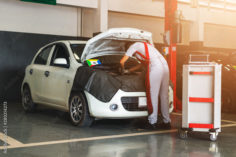 mechanic working car maintenance with soft-focus and over light in the background