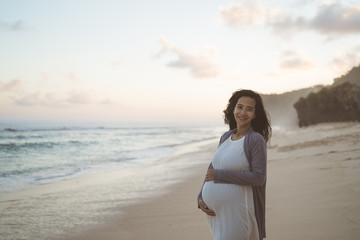 beautiful pregnant woman standing on the beach when sunrise in the morning