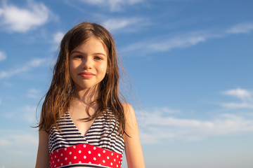 portrait of a beautiful happy young girl in swimsuit on the background of the sea and sky