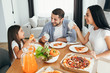 © Peakstock - happy multi ethnic family, mother, father and daughter during dinner.Eating delicious pizza with family