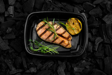 Wall Mural - Top view of grill cooked fish in take away box on coal
