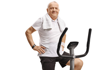 Wall Mural - Elderly man sitting on an exercise bike and looking at the camera