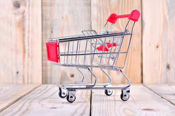 Single empty shopping cart on wooden background