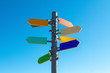 Guidepost with bright colored arrows against blue sky