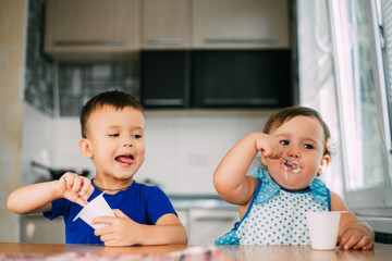 Wall Mural - Boy and Girl in the kitchen eating yogurt on a warm summer day