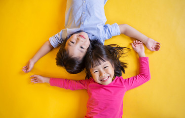 Portrait of young happy little asian boy girl in on yellow background. Education for preschool toddler, brother and sister lifestyle back to school together concept