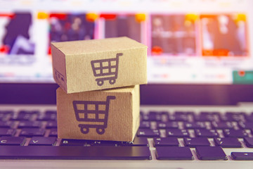 Online shopping - Paper cartons or parcel with a shopping cart logo on a laptop keyboard. Shopping service on The online web and offers home delivery.