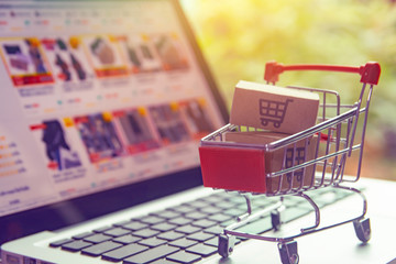 Shopping online concept - Parcel or Paper cartons with a shopping cart logo in a trolley on a laptop keyboard. Shopping service on The online web. offers home delivery.