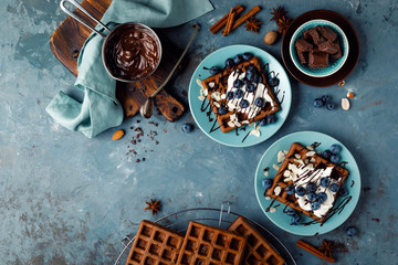 Sticker - Chocolate belgian waffles with ice cream and fresh blueberry on blue background, top view