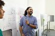 © Cavan Images - Smiling businessman explaining business plan over whiteboard in meeting at office