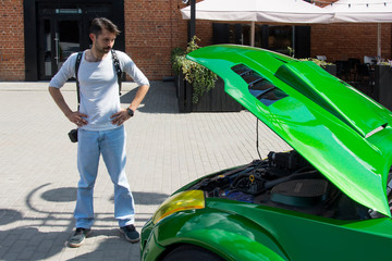 young man with a camera examines a car