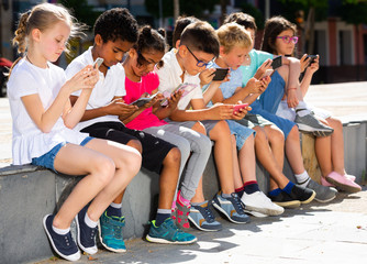 Eight kidsare chatting on their smartphone on walking