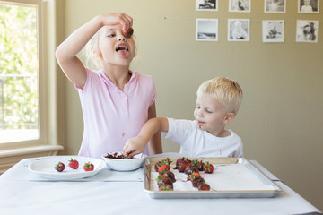 a little girl about to eat a chocolate strawberry she made