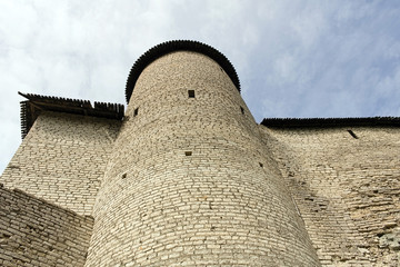 High round stone tower with a wooden roof of a medieval castle surrounded by walls of the fortress. Background with copyspace