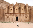 © julie - Woman stands in front of the Monastery at Petra in celebration with arms up in joy.