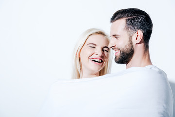 girlfriend and boyfriend covered in blanket laughing on white