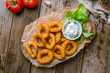 Onion rings in batter on the board on wooden background