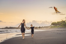 Mom And Son Are Running On The Sea Beach Launching A Kite
