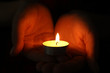 © New Africa - Woman holding burning candle in darkness, closeup