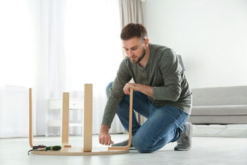 Poster - Young working man repairing table at home