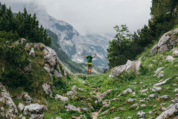 Hiker man standing with hands up achieving the pass. Conceptual design. Successful man hiker open arms on mountain pass. Man in sportswear in the mountains. Montenegro, Durmitor National Park