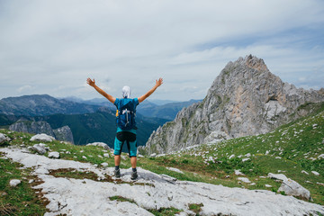 Hiker man standing with hands up achieving the top. Conceptual design. Successful man hiker open arms on mountain top. Man in sportswear in the mountains. Montenegro, Prokletije National Park