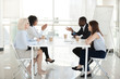 © fizkes - Diverse employees sit at table, discussing project in boardroom