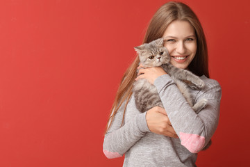 Beautiful young woman with cute cat on color background