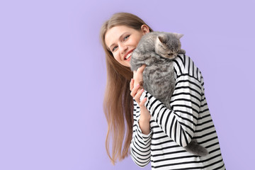 Beautiful young woman with cute cat on color background