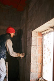 Fototapeta Sport - Real construction worker making a wall inside the new house.