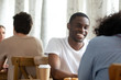 © fizkes - Happy smiling black guy sitting in coffeehouse with friend.