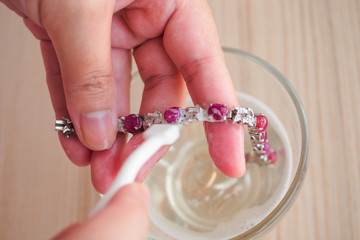 Wall Mural - Jeweller hand cleaning and polishing vintage jewelry red ruby bracelet closeup