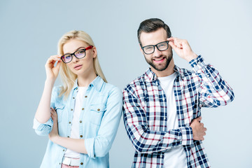 man and girl adjusting glasses and looking at camera on grey