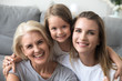 © fizkes - Happy laughing granddaughter mother and grandmother looking at camera