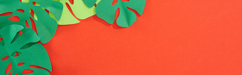 panoramic shot of green paper cut tropical leaves on bright red background with copy space