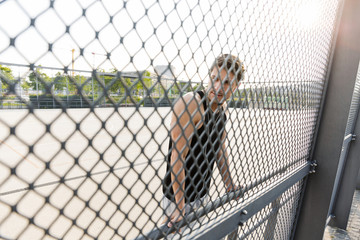 Wall Mural - Photo of young man wearing earphones standing on sports ground during morning workout outdoors