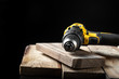 © no - Electric drill closeup on a black background with wood and drills. Electrical tools. Hand battery screwdriver.