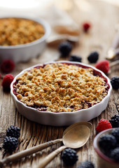 Wall Mural - Mixed berry (blackberry, raspberry) crumble in a baking dish on a wooden table, close-up