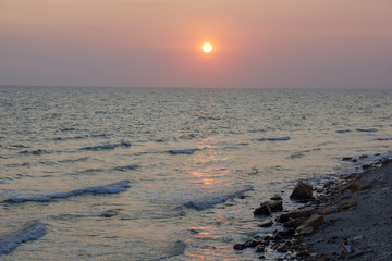 Wall Mural - seascape sunset the sun sets the sea wave the sea foam. stones coast